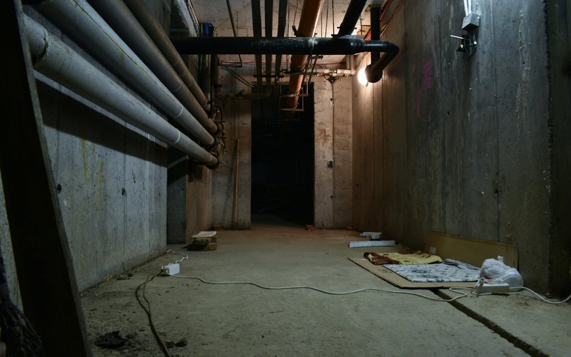a dark room with pipes and a sheet of paper on the floor