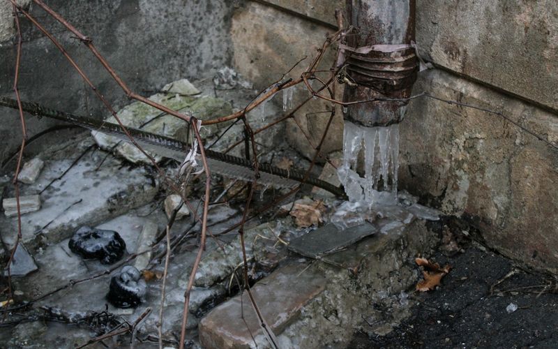 a fire hydrant next to a wall with ice on it