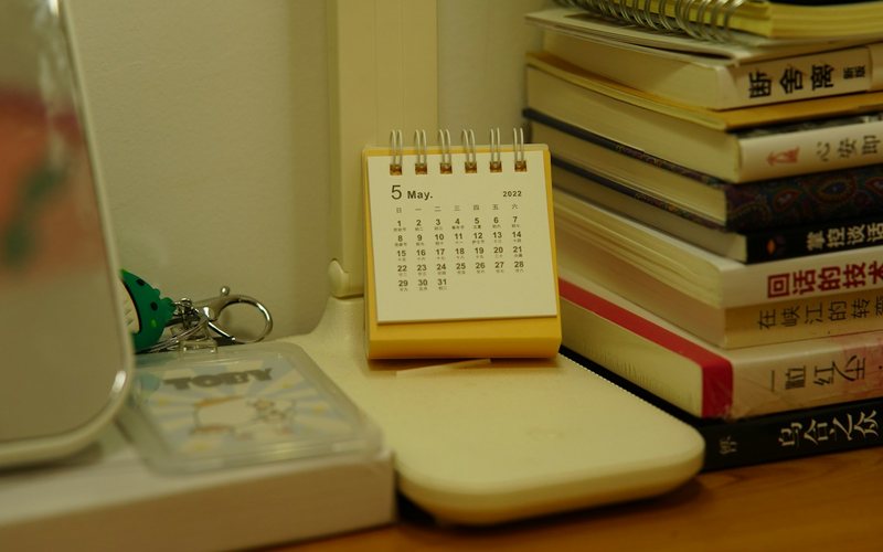 A small desk calendar sits beside a stack of books