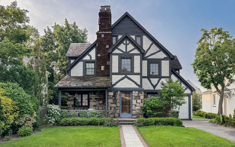 A charming tudor-style home with a beautiful yard