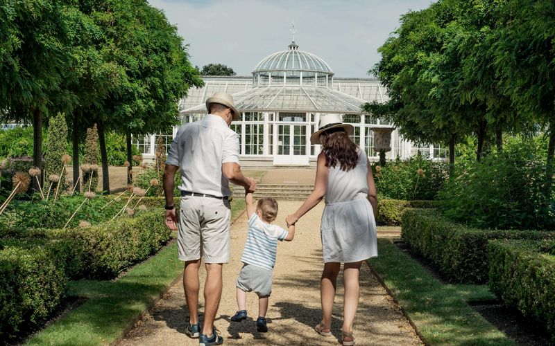 woman and man holding child while walking leading to house