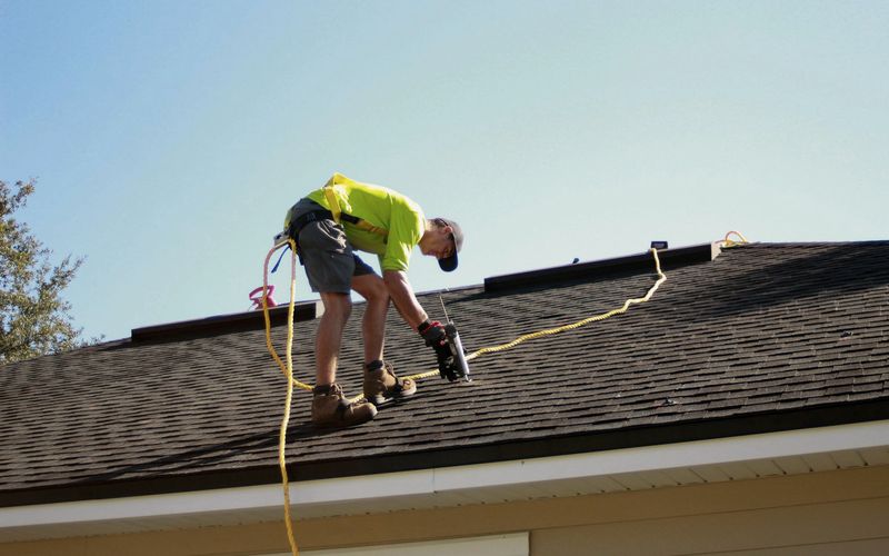 a man working on a roof with a power drill