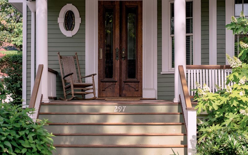 brown wooden rocking chair on porch beside closed French doors