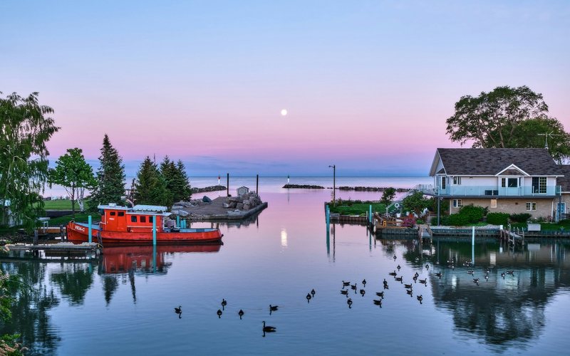 Calm waterway with boats at pastel sunset
