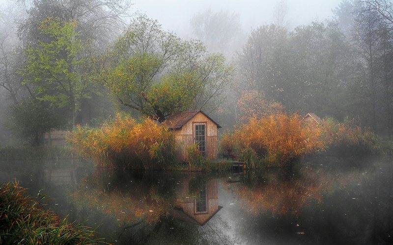 a small house sitting on top of a lake surrounded by trees