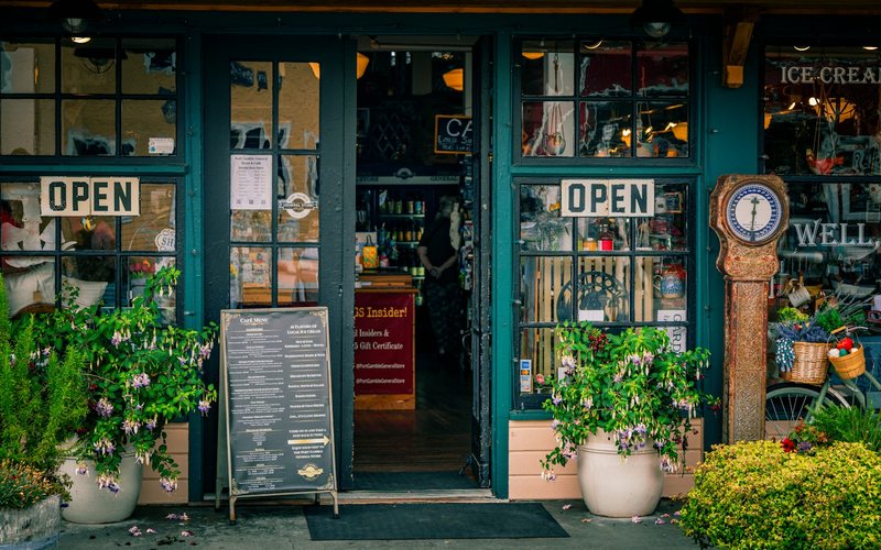 Green storefront with open signs and plants