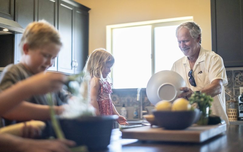 Grandfather and grandchildren prepare food in kitchen