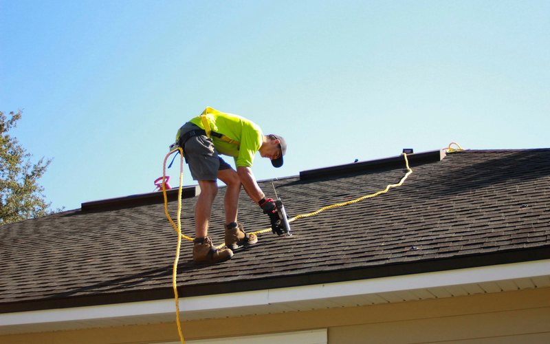 a man working on a roof with a power drill