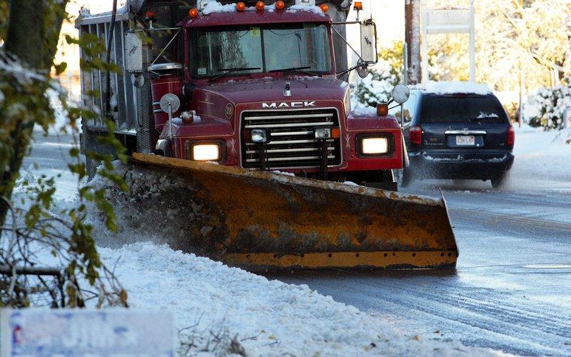 a snow plow driving down a snow covered road