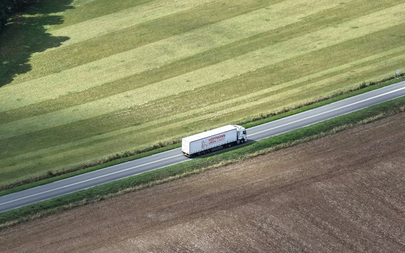 White truck driving on a road through fields